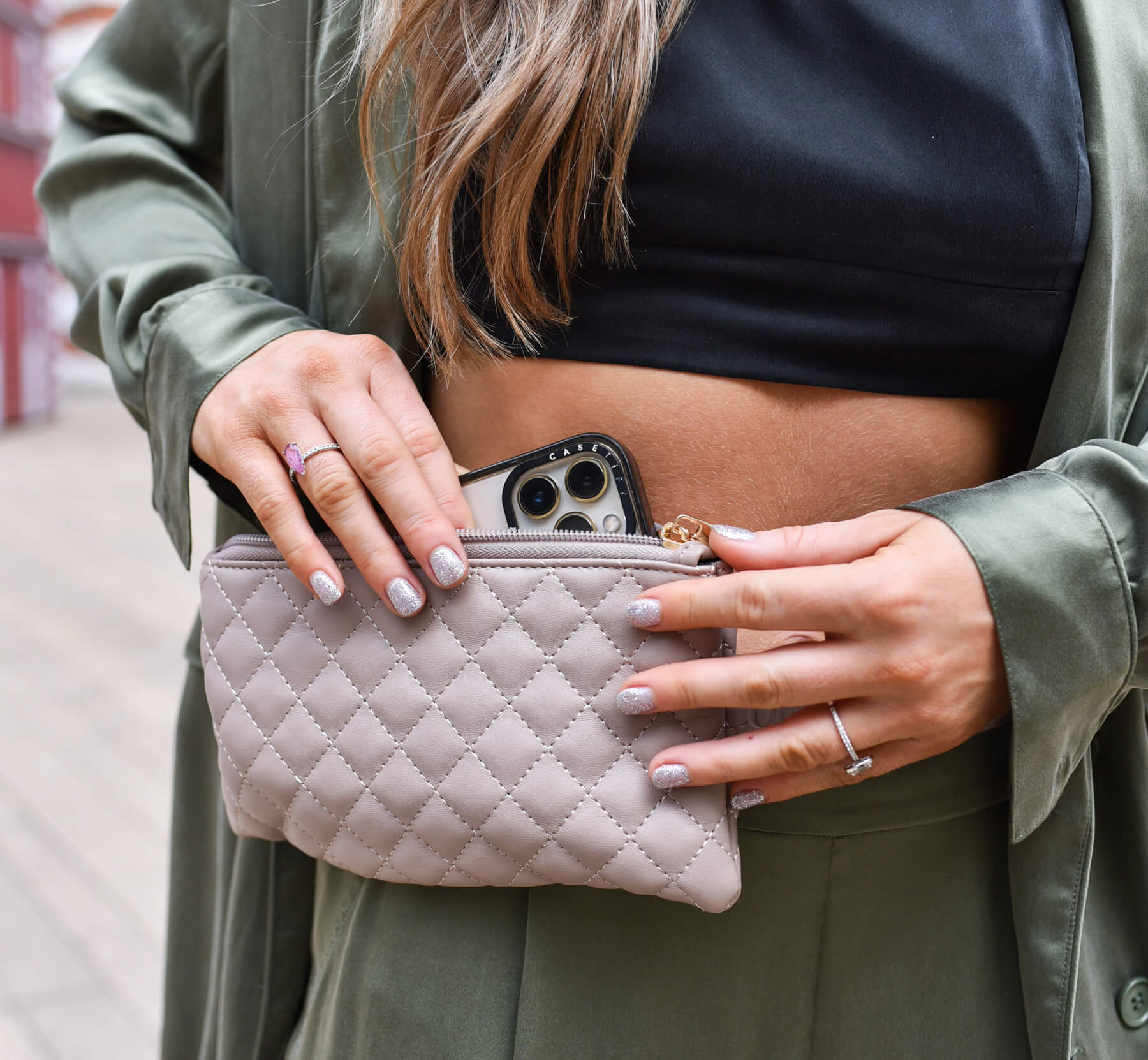 Close up of woman putting her phone into The Coco Alexander Mini in neutral