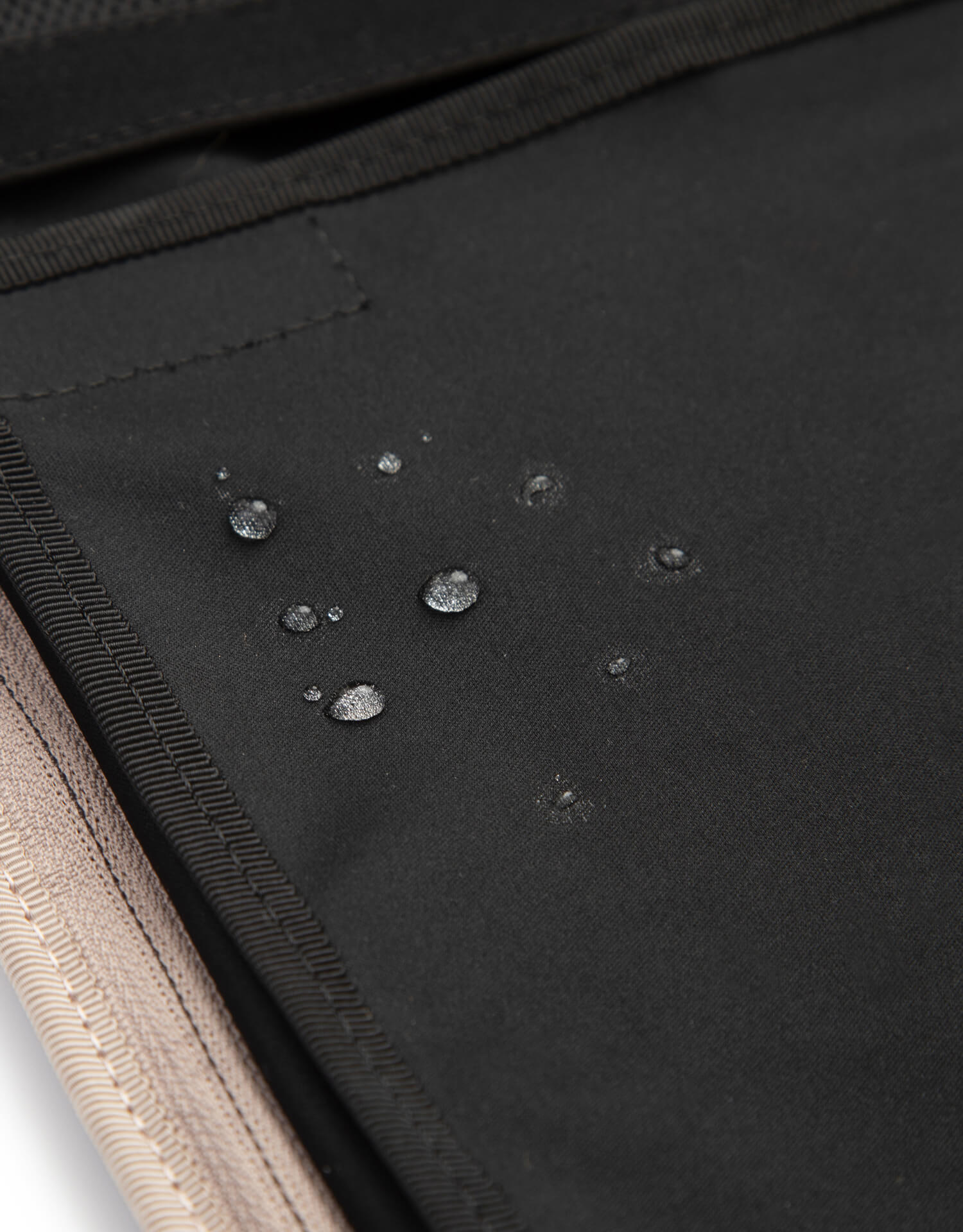 Diaper bag open with water droplets to show the inner is water repellent